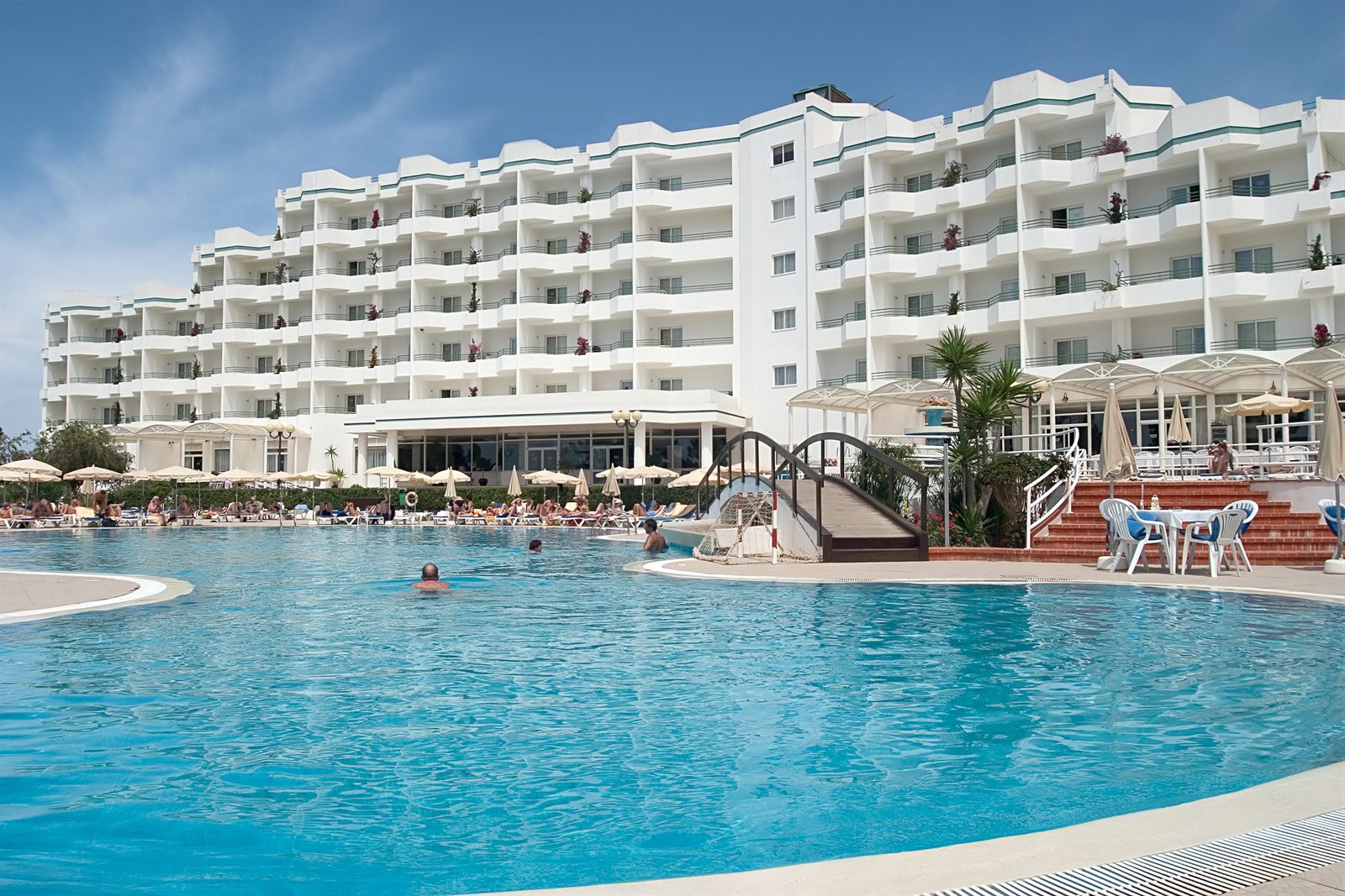 Hotel swimming pool in front of a white hotel building
