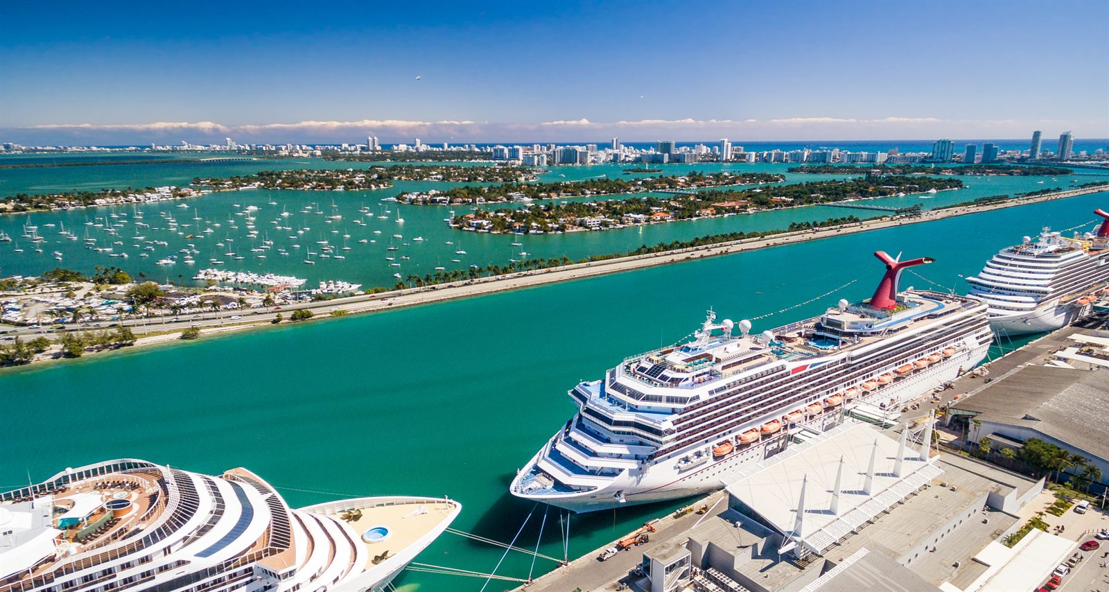 Cruise ships berthed at port terminals with parking structures alongside