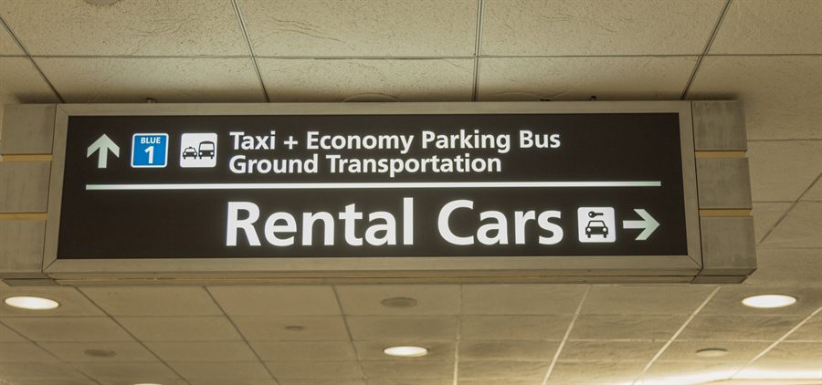 Overhead sign pointing to taxis, economy parking bus and rental cars